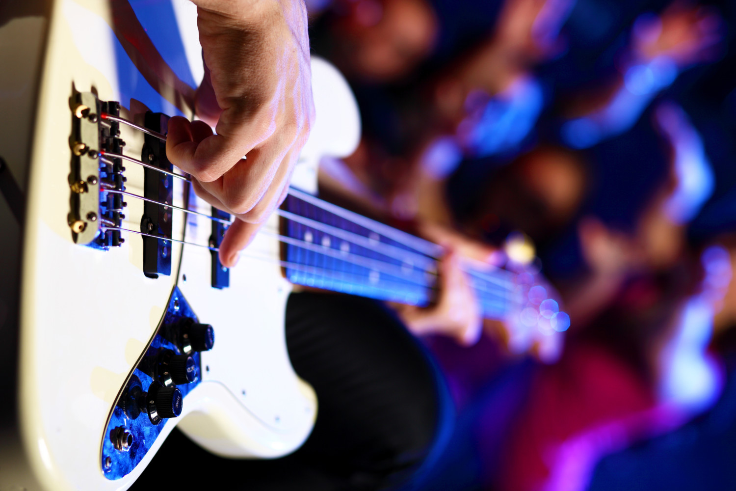 Young guitar player with instrument performing in night club